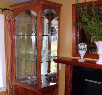 Pair of arched African Bubinga display cabinets flanking a fireplace