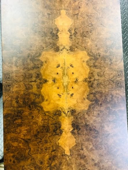 Top-down view of the burl walnut tier showing the dramatic four-way book-matched veneer pattern with a glowing central figure surrounded by darker burl.