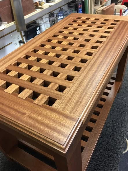 Mahogany coffee table with a top composed of half-lapped interlocking square lattice sections, framed by a clean mahogany border, with a matching slatted lower shelf.