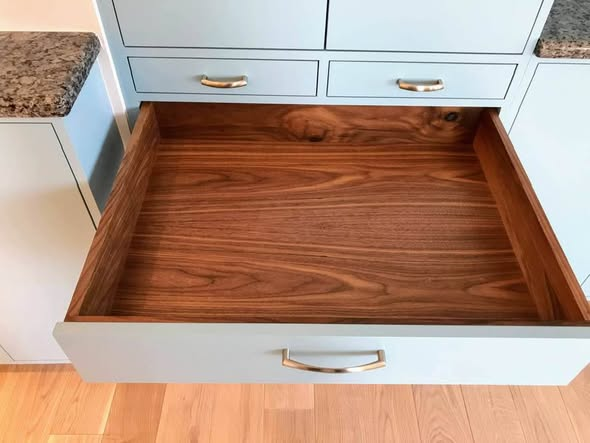 Open dovetailed solid walnut drawer in the Penn Ave kitchen with brass bow pull