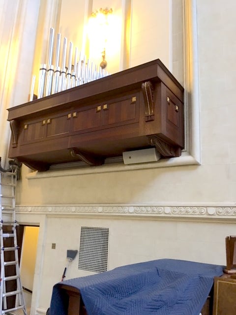 Quarter-sawn white oak pipe organ box installed beside the altar in the US Naval Academy Chapel, with recessed flat panels and gold-leafed rosettes