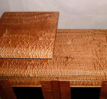 Detail of Pommelle Sapele cabinet showing figured grain, bead detail, and two-tier top on six-inch posts