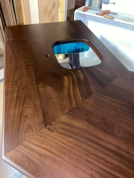 Close-up of the Sapele mahogany island top showing the rounded undermount sink cutout, mitered corner, and rich ribbon grain.