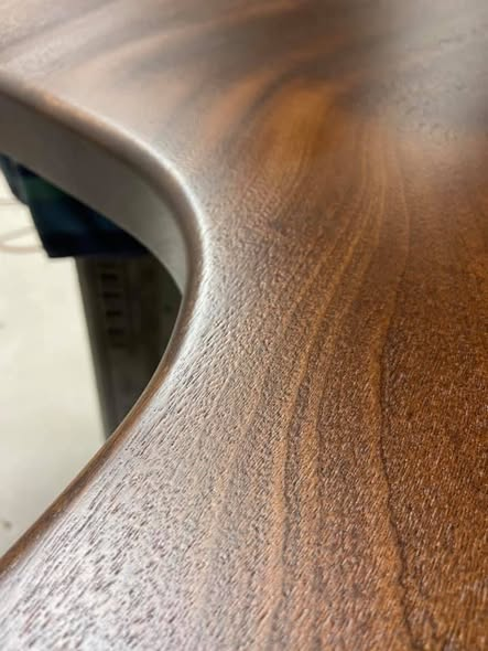 Macro detail of the Sapele mahogany island top showing the smooth eased edge around the sink cutout and the deep figured grain of the wood.