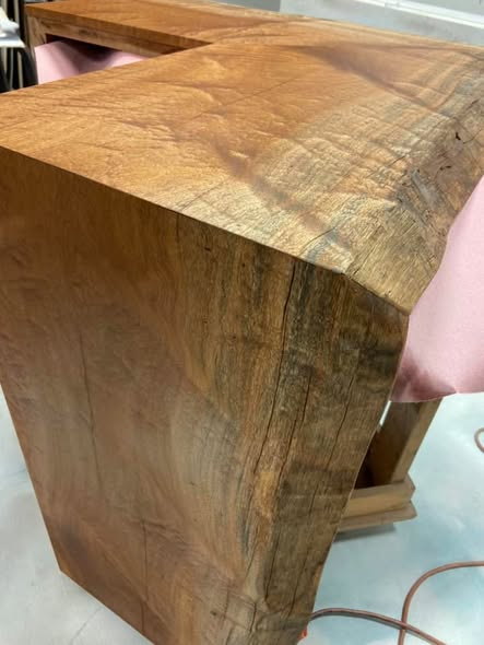 Close-up of the Sapele mahogany waterfall corner showing the mitered grain wrap, live edge, and dramatic figure in the wood.