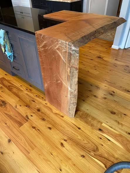 Full waterfall end of the Sapele mahogany island cascading down to the wood floor next to a painted island base.