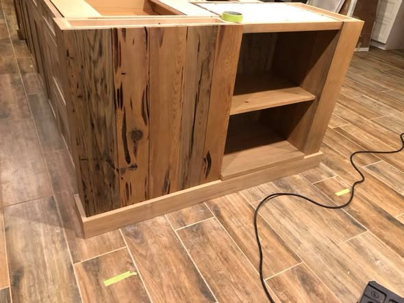End view of the sinker cypress kitchen island showing the pecky cypress panel end, clear cypress framing, and base detail