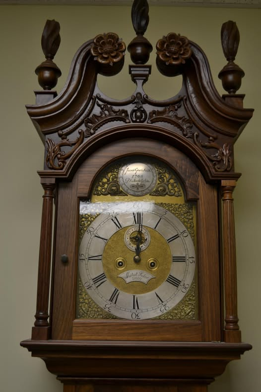 Restored 18th-century Philadelphia tall-case clock hood with swan-neck bonnet, carved rosettes, flame finials, fluted columns, and engraved brass dial with silvered chapter ring