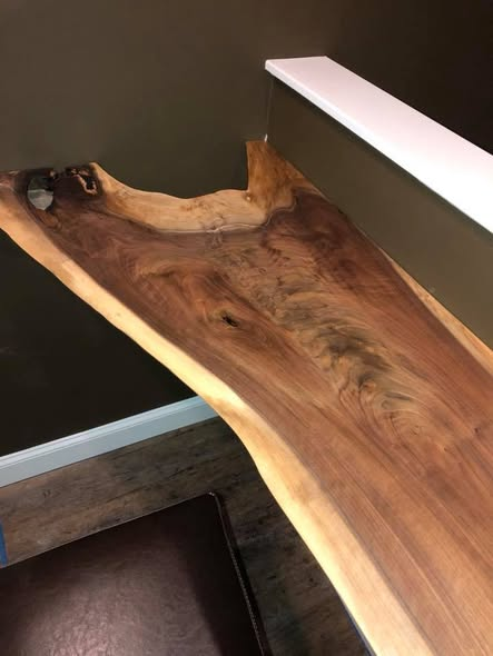 Live-edge walnut slab bar top in a home theater room, showing the natural curving edge, light sapwood, dark heartwood figure, and low-sheen clear coat.