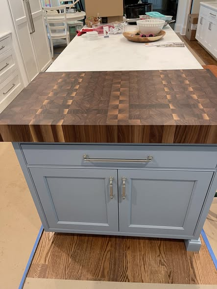 3-inch thick walnut end grain butcher block top installed on a soft blue painted island base with brushed nickel hardware in a bright white kitchen.