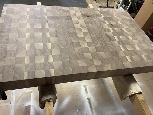 Unfinished 3-inch thick walnut end grain butcher block resting on sawhorses in the shop, showing the dramatic checkerboard pattern of end grain blocks.