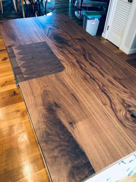 Walnut kitchen island top with rich figured grain and a recessed end-grain walnut cutting board inset flush with the surface.