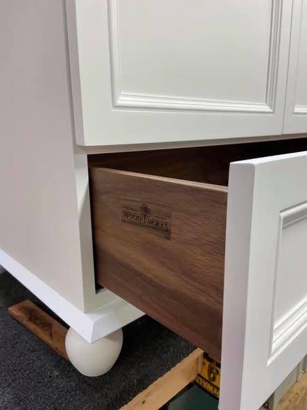 Open walnut dovetailed drawer in the white vanity, branded with the shop's woodworks maker's mark on the drawer face