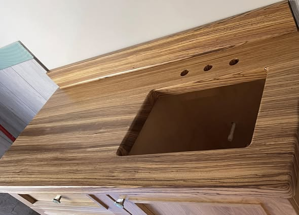 Installed Zebrano vanity top with sink cutout and faucet holes, showing the dramatic striped grain running across the surface